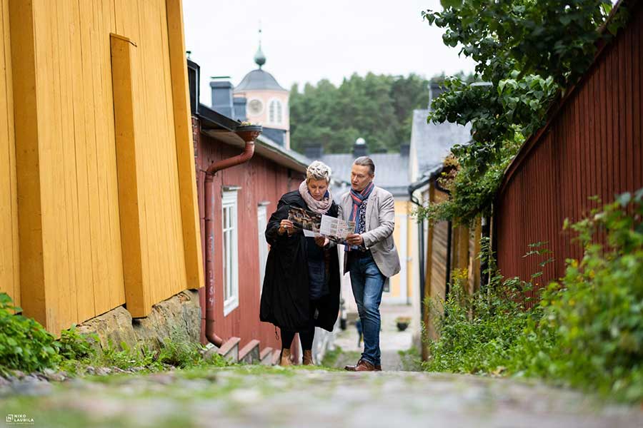 Matkailijoita Porvoon vanhassa kaupunkissa, tutkivat matkaopasta.
